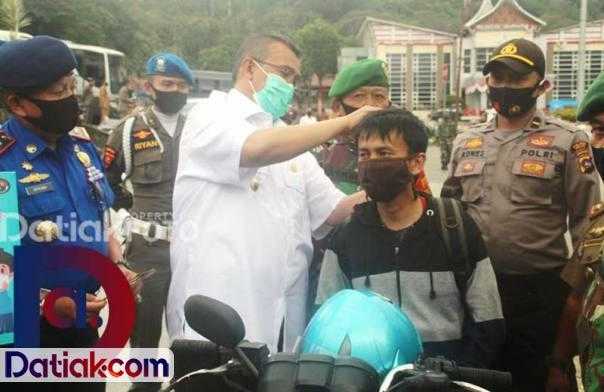 Bupati Solok Gusmal ketika memasangkan masker kepada pengendara sepeda motor yang tidak bermasker. Untuk penerapan protokol kesehatan, seluruh pihak terkait hingga nagari diminta aktif sosialisasikan Perda AKB Sumbar. (Foto: Humas)
